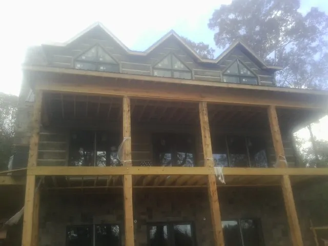 Dormers and porch framing on a large log home under construction — Roof Coating work by our crew in Athens